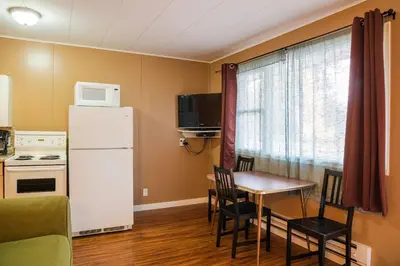 a small kitchen with a table and a white refrigerator at Lakeview Motel in Christina Lake