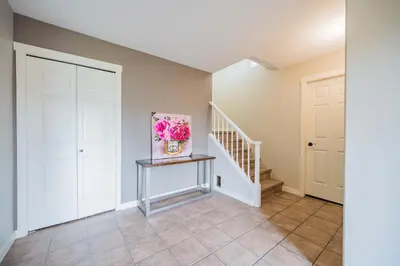 a hallway with white doors and a staircase with a painting at Cozy 5BD House in North Mission Crawford in Kelowna