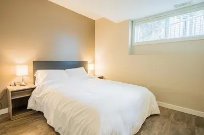 a bedroom with a large white bed and a window at Cozy 5BD House in North Mission Crawford in Kelowna
