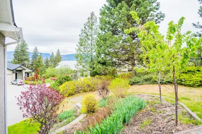 a garden with trees and flowers in a yard at Cozy 5BD House in North Mission Crawford in Kelowna