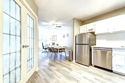 a kitchen with a table and a stainless steel refrigerator at Roomy Top Floor at Stampede w Free Parking and AC in Calgary