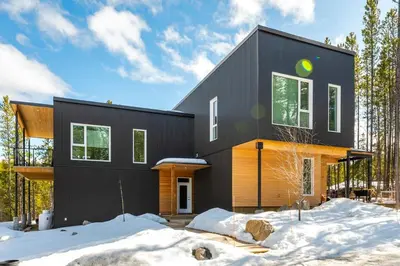 a black house in the woods in the snow at NN War Eagles Nest Ravens Ridge 1bed 1 bath in Whitehorse