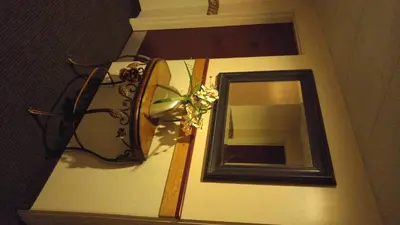 a mirror on a wall with a lamp and flowers at Crossfield Country Inn in Crossfield