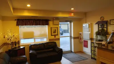 a living room with a leather chair and a door at Crossfield Country Inn in Crossfield