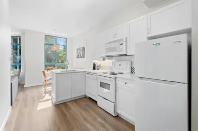 a kitchen with white cabinets and a refrigerator at Alpenglow Lodge West Coast Wonder by MVA in Whistler