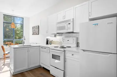 a white kitchen with white cabinets and appliances at Alpenglow Lodge West Coast Wonder by MVA in Whistler