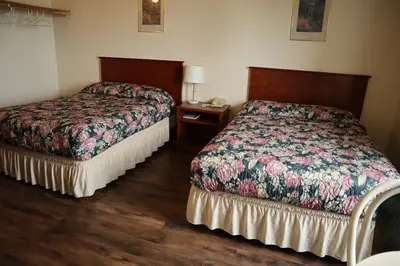 a hotel room with two beds and a night stand at Destination Family Hotel in Whitehorse