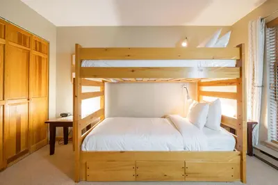 a bedroom with two bunk beds and a desk at Forest Trails by Outpost Whistler in Whistler