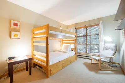 a bedroom with a bunk bed and a desk and a chair at Forest Trails by Outpost Whistler in Whistler