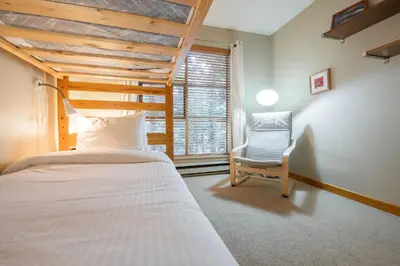 a bedroom with a bed and a chair and a window at Forest Trails by Outpost Whistler in Whistler