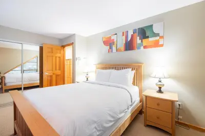a bedroom with a large white bed and a mirror at Forest Trails by Outpost Whistler in Whistler