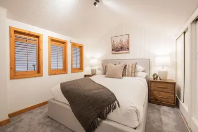 a white bedroom with a bed and two windows at Powderview by Outpost Whistler in Whistler