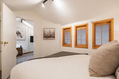 a bedroom with a white bed and windows at Powderview by Outpost Whistler in Whistler