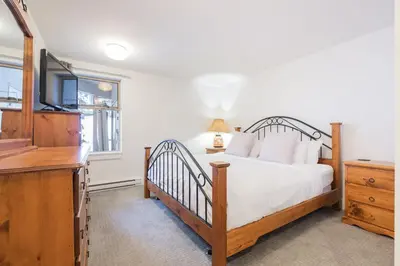 a bedroom with a bed with a television and a dresser at Gleneagles by Outpost Whistler in Whistler