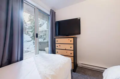 a bedroom with a tv and a dresser with a bed at Gleneagles by Outpost Whistler in Whistler