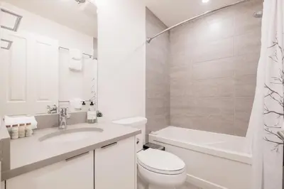 a white bathroom with a sink and a toilet and a tub at Lake Placid Lodge by Outpost Whistler in Whistler