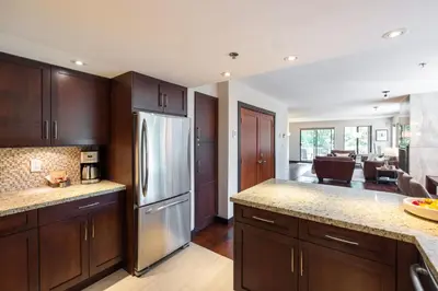 a kitchen with wooden cabinets and a stainless steel refrigerator at Greyhawk 123 by Outpost Whistler in Whistler