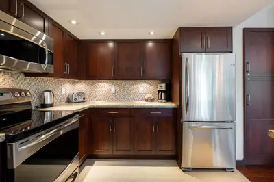 a kitchen with wooden cabinets and a stainless steel refrigerator at Greyhawk 123 by Outpost Whistler in Whistler