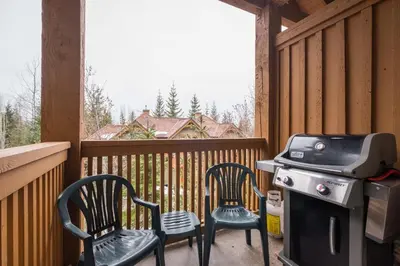a screened in porch with two chairs and a grill at Mountain Star by Outpost Whistler in Whistler