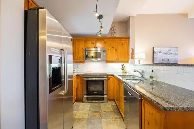 a kitchen with wooden cabinets and a stainless steel refrigerator at Mountain Star by Outpost Whistler in Whistler