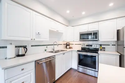 a white kitchen with white cabinets and a sink at Lynx by Outpost Whistler in Whistler