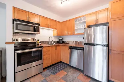 a kitchen with wooden cabinets and stainless steel appliances at Glacier's Reach by Outpost Whistler in Whistler