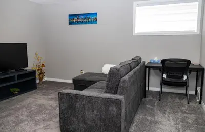 a living room with a couch and a table and a television at The Jade Place in Airdrie