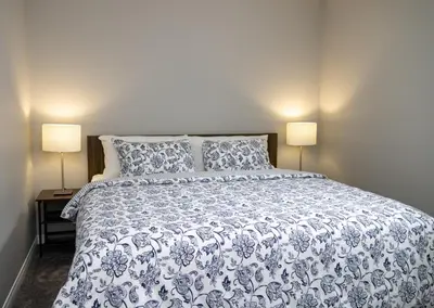 a bedroom with a blue and white bed with two lamps at The Jade Place in Airdrie
