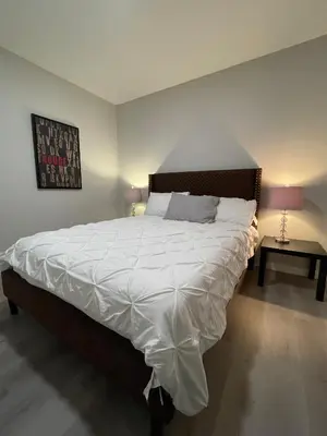 a bedroom with a large bed with white sheets at Private Chic Modern Suite with Kitchen near Spruce Meadows and LRT in Calgary
