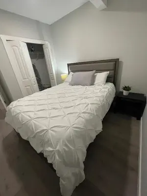 a bedroom with a large bed with a white comforter at Private Chic Modern Suite with Kitchen near Spruce Meadows and LRT in Calgary