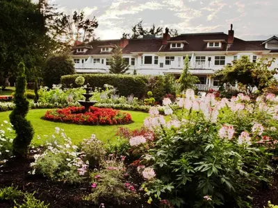 a garden in front of a house with flowers at Crown Mansion Boutique Hotel & Villas in Qualicum Beach