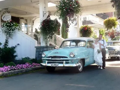 a bride and groom standing next to a blue car at Crown Mansion Boutique Hotel & Villas in Qualicum Beach