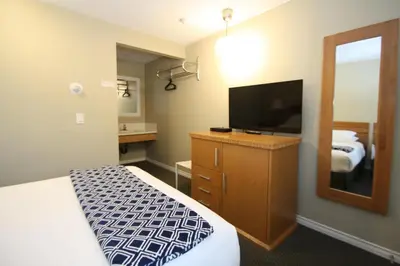 a hotel room with a bed and a flat screen tv at Harrison Spa Motel in Harrison Hot Springs