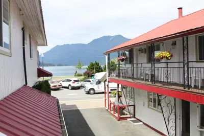 a building with a balcony with flowers in a parking lot at Harrison Spa Motel in Harrison Hot Springs