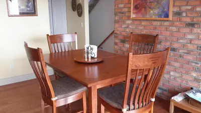 a dining room table with chairs and a brick wall at Casa Loma BnB in West Kelowna