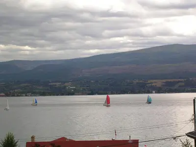 three sailboats on a lake with mountains in the background at Casa Loma BnB in West Kelowna