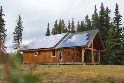 a house with solar panels on it in a field at Red Cariboo Resort in Anahim Lake