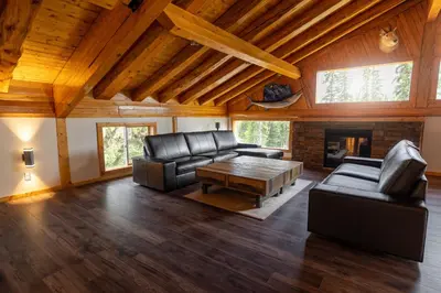 a living room with leather furniture and a fireplace at Red Cariboo Resort in Anahim Lake