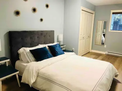 a bedroom with a large bed with blue pillows at Olympic Views - Cozy Modern 2Br Suite in Victoria