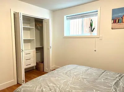 an empty bedroom with a bed and a window at Newly Renovated Walkout Basement in Vancouver with Separate Entrance in Vancouver
