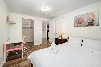 a white bedroom with a white bed and a desk at Gorgeous 4 Bedroom Garden Level Suite at Vancouver West & UBC in Vancouver