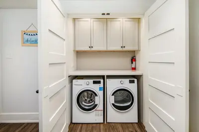 a laundry room with white cabinets and a washer and dryer at Gorgeous 4 Bedroom Garden Level Suite at Vancouver West & UBC in Vancouver