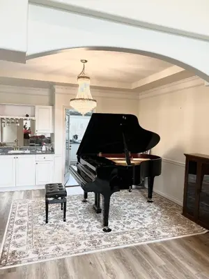 a black piano in a kitchen with a chandelier at Master Bedroom with Two Queen Sized Bed in Richmond
