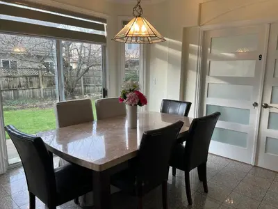 a dining room table with chairs and a vase of flowers at Master Bedroom with Two Queen Sized Bed in Richmond