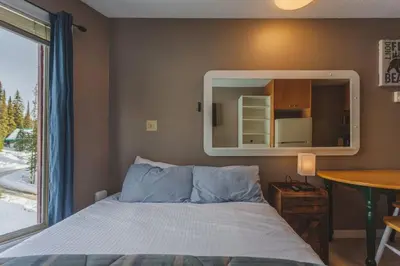 a bedroom with a bed and a mirror and a table at The Ridge Ski-In Ski-Out Condo with Free Parking in Big White