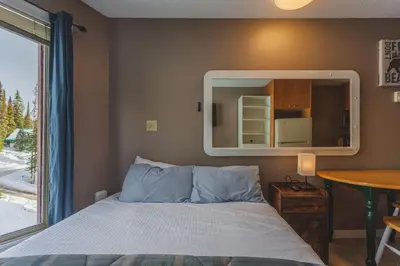 a bedroom with a bed with a mirror and a table at The Ridge Ski-In Ski-Out Condo with Free Parking in Big White