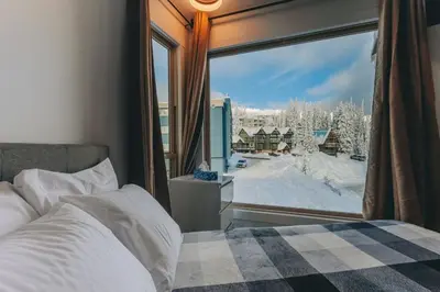a bedroom with a bed and a window with a winter view at The Fjall Ski-In Ski-Out Village Studio in Big White