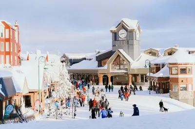 a group of people walking around a town in the snow at The Fjall Ski-In Ski-Out Village Studio in Big White