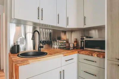 a kitchen with white cabinets and a sink at The Fjall Ski-In Ski-Out Village Studio in Big White