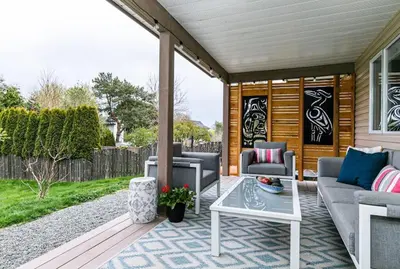 a patio with couches and a table on a porch at Lovely 2 bedroom suite steps from The beach in Victoria